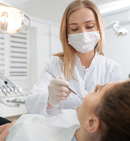 Female dentist with mask treating patient