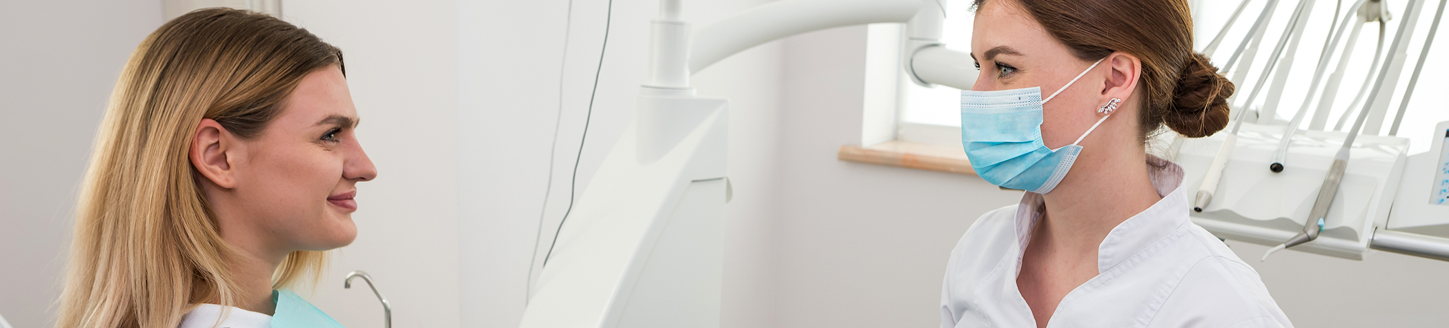 Female dentist with mask talking with female patient