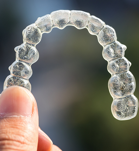 Hand holding ClearCorrect clear aligner