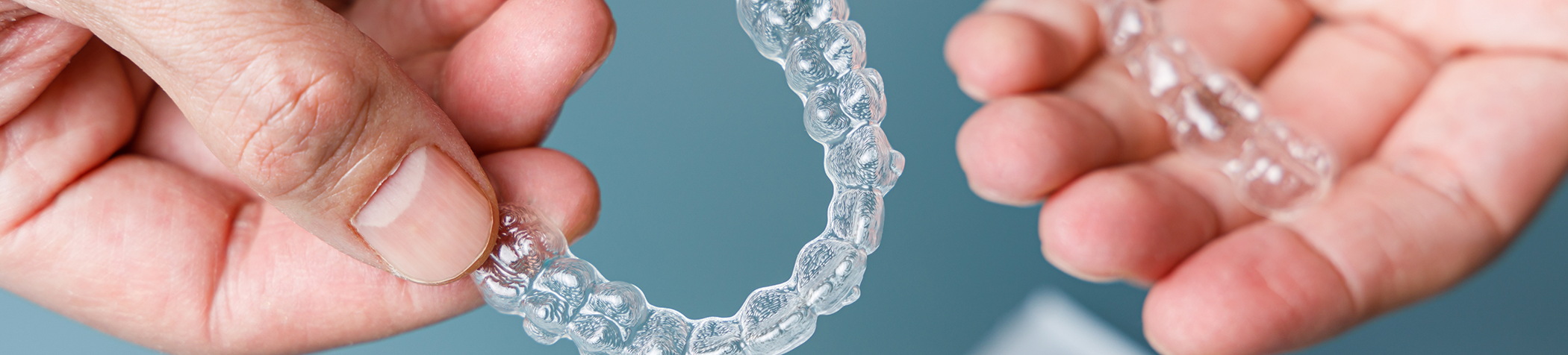 Close up of hands holding clear aligners