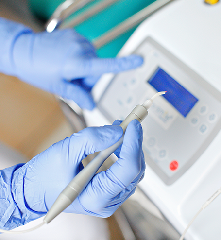 Gloved hands holding a diode dental laser