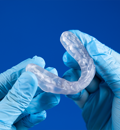 Gloved hands holding a nightguard