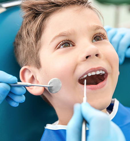 Little boy having teeth examined by dentist