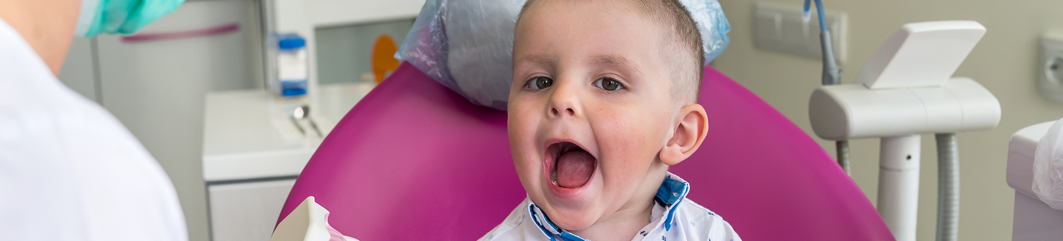 Little boy in dental chair opening mouth for dentist