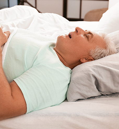 Older man snoring in bed